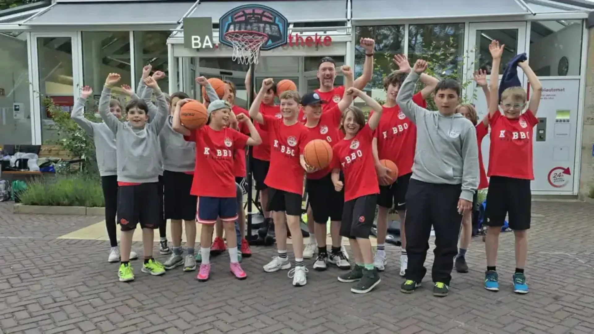 Jugend-Basketballgruppe mit erhobenen Armen und Basketbällen