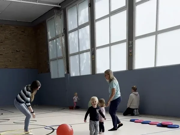Bunte Reifen und Bälle auf dem Hallenboden beim Eltern-Kind-Turnen, Standbild aus dem Vereinsvideo