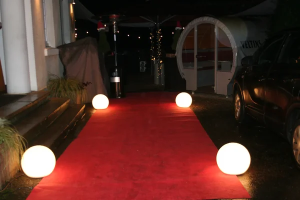 Roter Teppich mit Leuchtkugeln am Eingang zum Fest