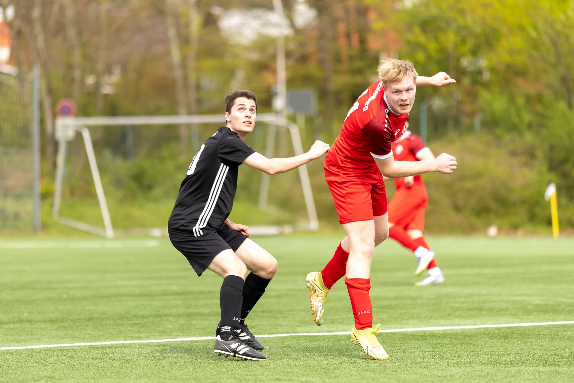 Fußballspieler im roten Trikot im Kopfballduell