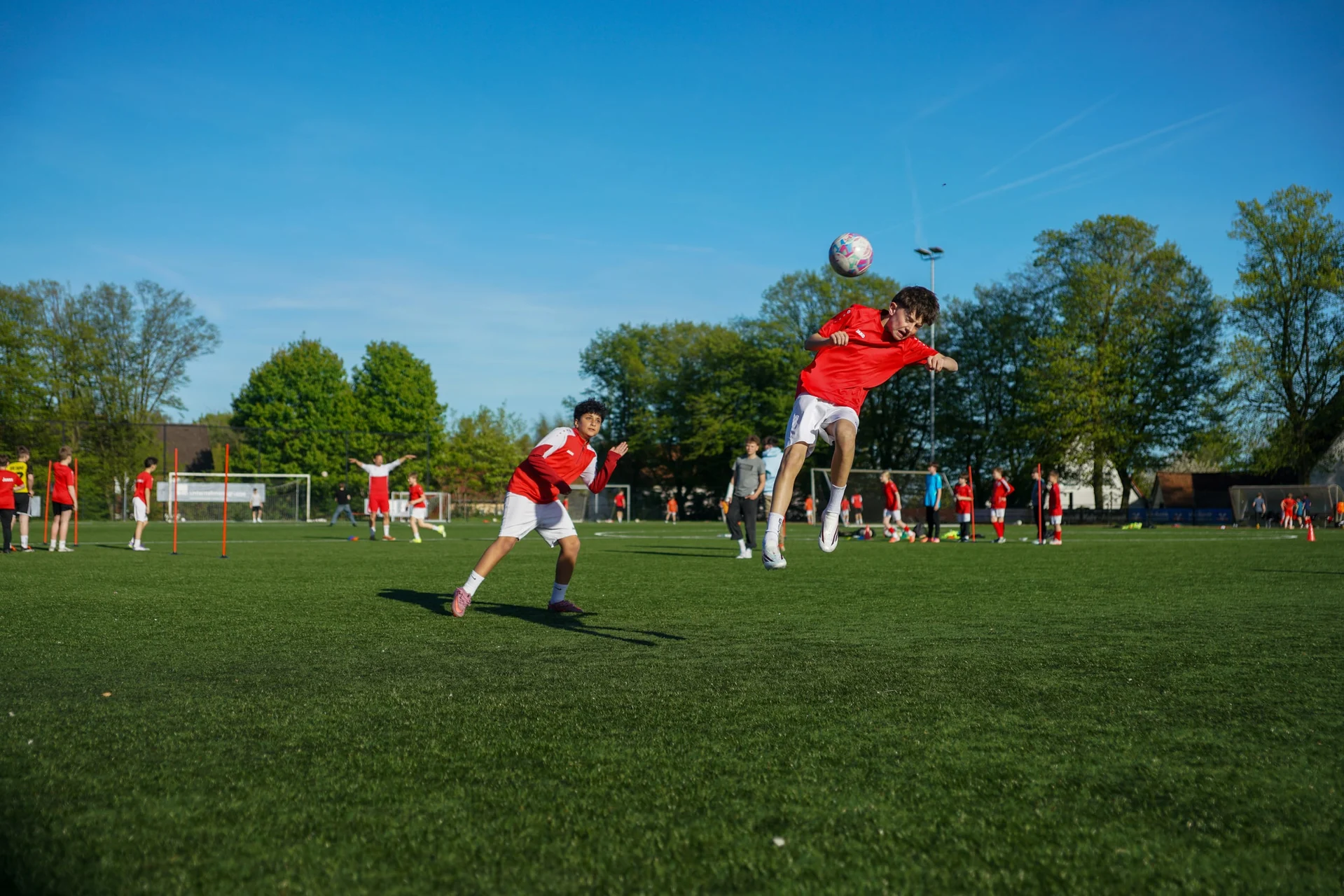 Spieler springt im Kopfballduell in den blauen Himmel