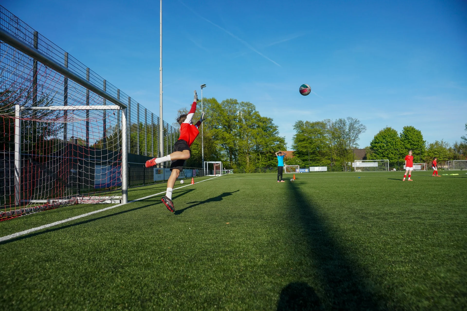 Torwart springt auf dem Sportplatz zum Ball