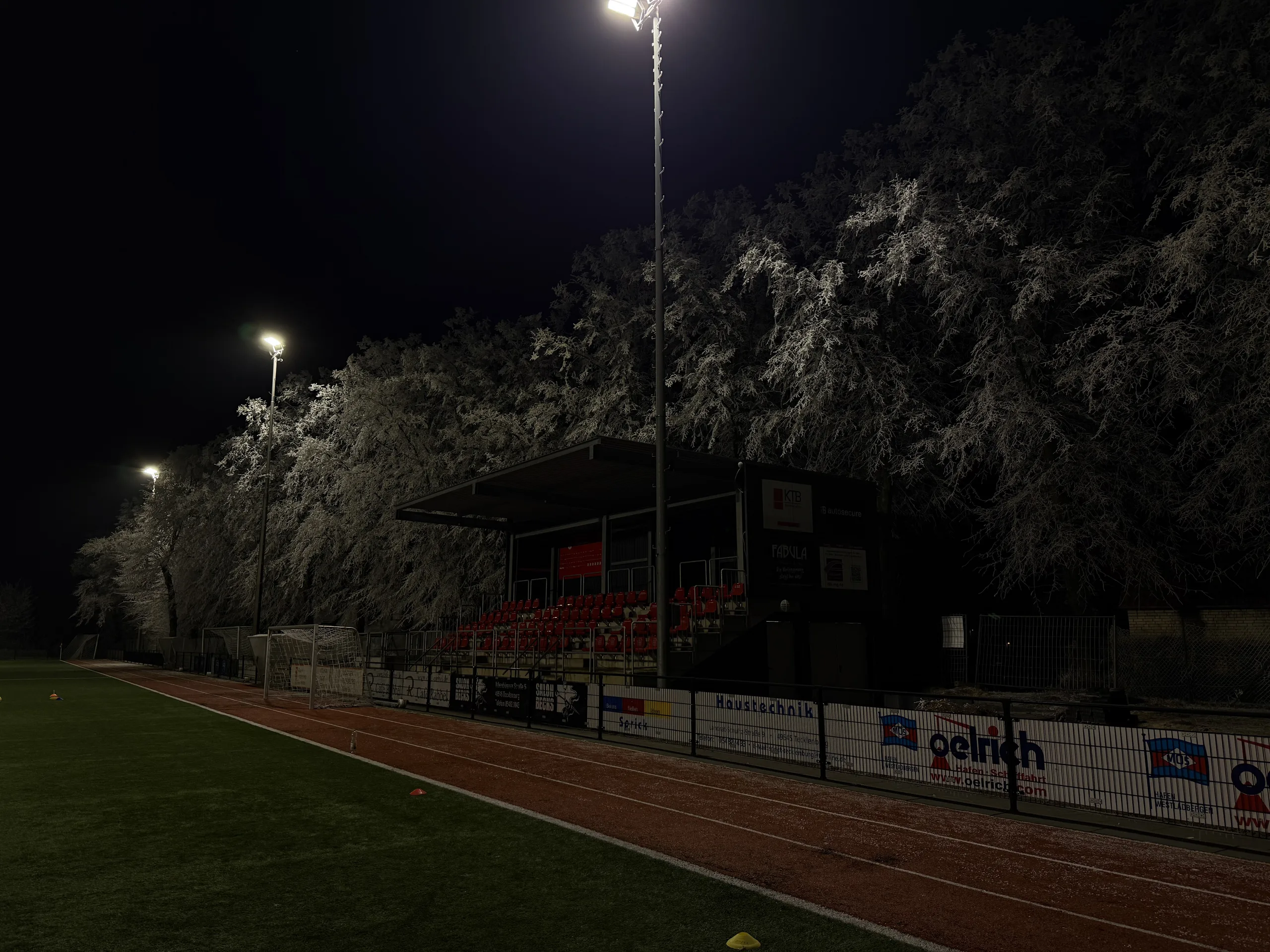Tribüne und Bandenwerbung im Flutlicht
