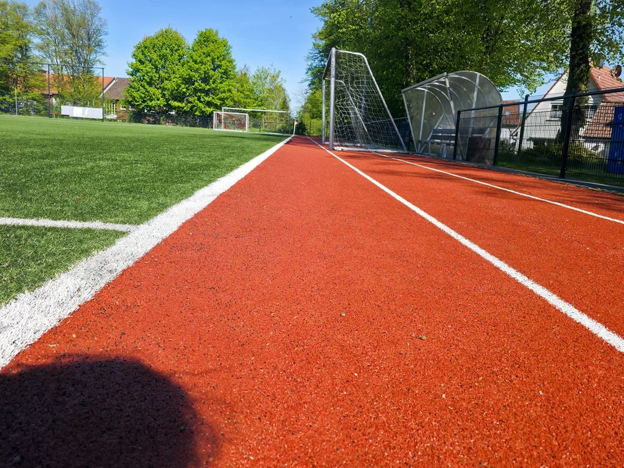 Laufbahn und Sportplatz der Vereinsanlage im Sonnenlicht