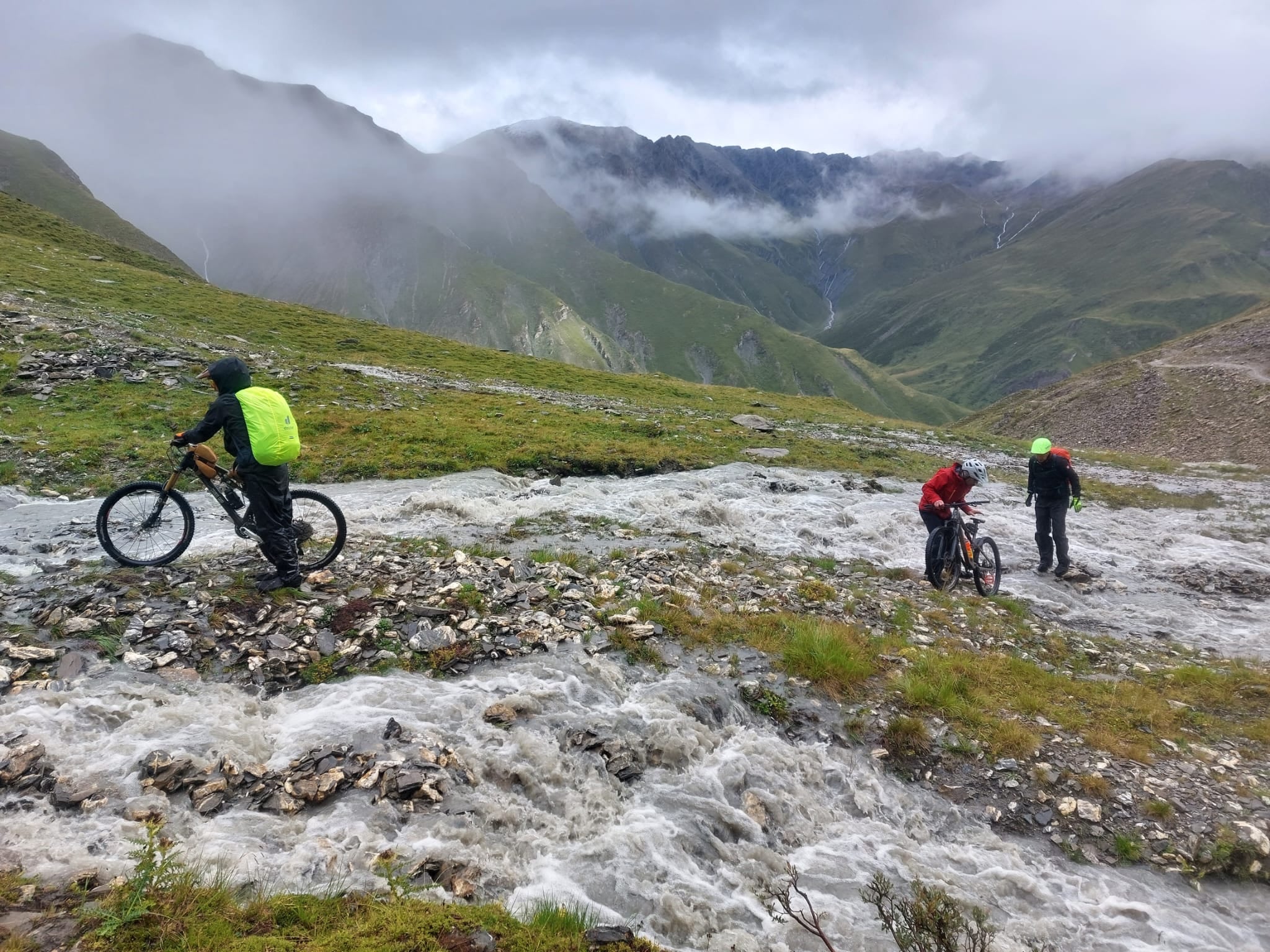 Mountainbiker hält sein Rad in dichtem Nebel über den Kopf, Blick auf einen Bergpfad